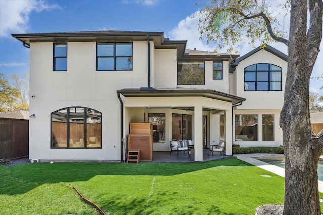 back of house featuring stucco siding, a lawn, and a patio