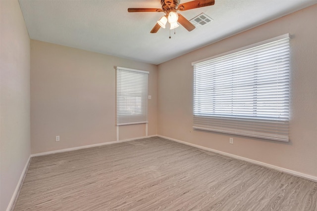 empty room with visible vents, baseboards, ceiling fan, and wood finished floors