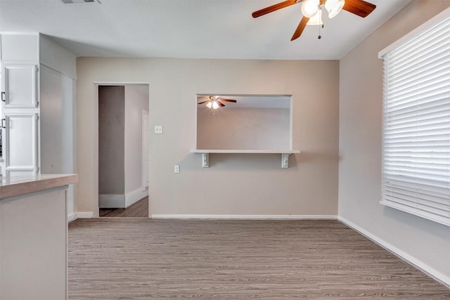 unfurnished living room featuring wood finished floors, baseboards, and ceiling fan