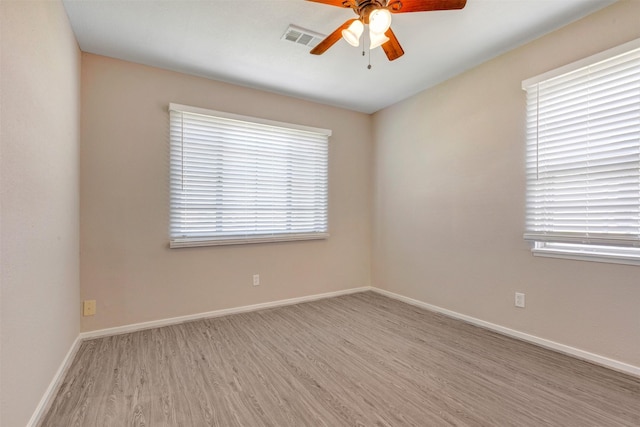 empty room with baseboards, wood finished floors, visible vents, and ceiling fan