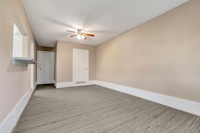 empty room featuring baseboards, wood finished floors, and a ceiling fan