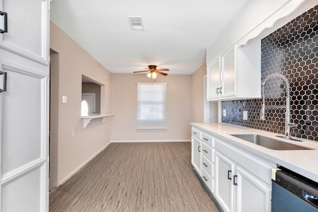 kitchen featuring visible vents, a sink, white cabinetry, decorative backsplash, and dishwasher