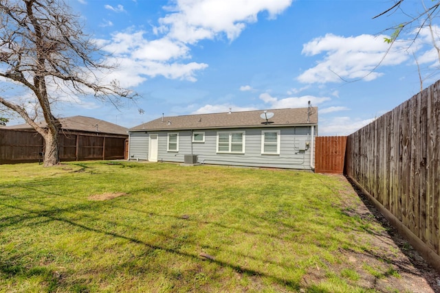 rear view of property featuring a fenced backyard, central AC, and a yard