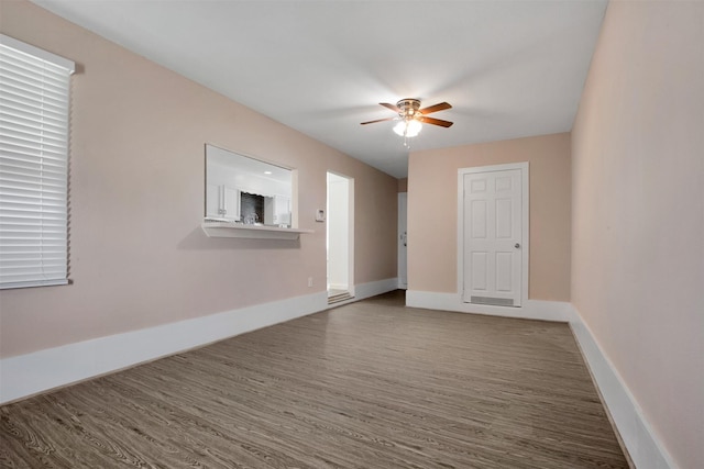 unfurnished room featuring wood finished floors, baseboards, and ceiling fan