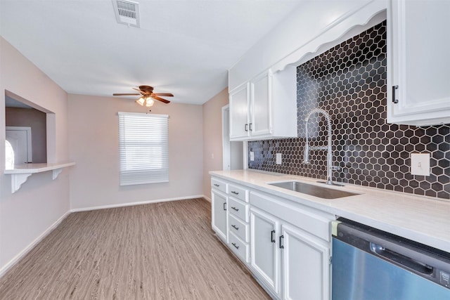 kitchen featuring stainless steel dishwasher, light countertops, decorative backsplash, and a sink