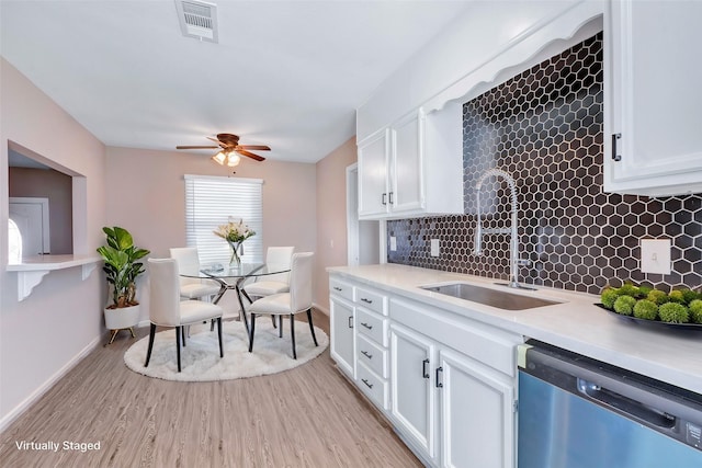 kitchen featuring a sink, dishwasher, white cabinets, and light countertops