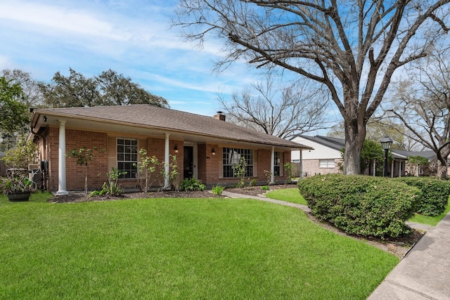 single story home with a front yard, brick siding, and a chimney