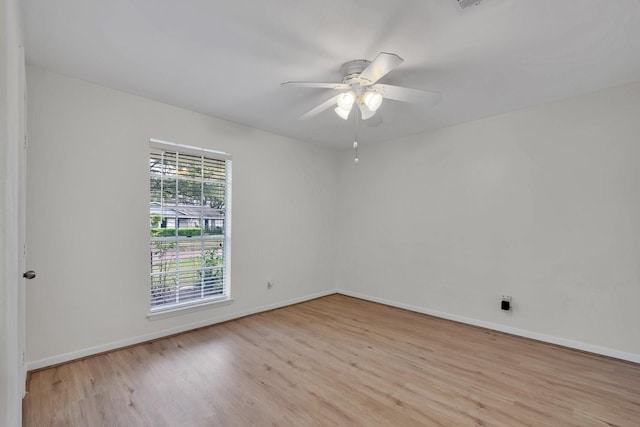 spare room featuring baseboards, light wood-type flooring, and ceiling fan