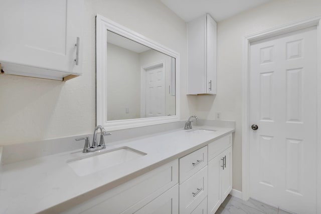 full bath with a sink, marble finish floor, and double vanity