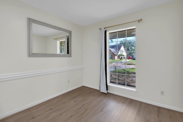 spare room featuring baseboards and wood finished floors