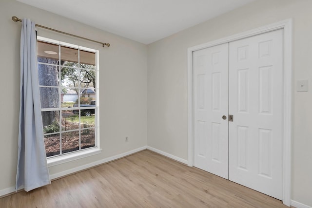 unfurnished bedroom with a closet, baseboards, and wood finished floors