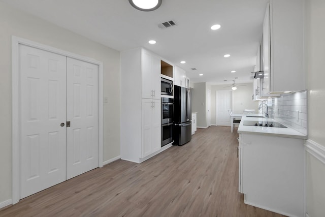 kitchen with light wood finished floors, visible vents, light countertops, white cabinets, and stainless steel appliances