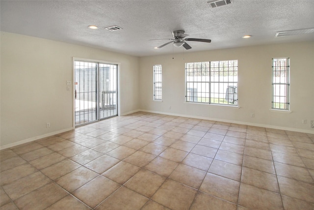 tiled empty room with visible vents, a textured ceiling, baseboards, and ceiling fan