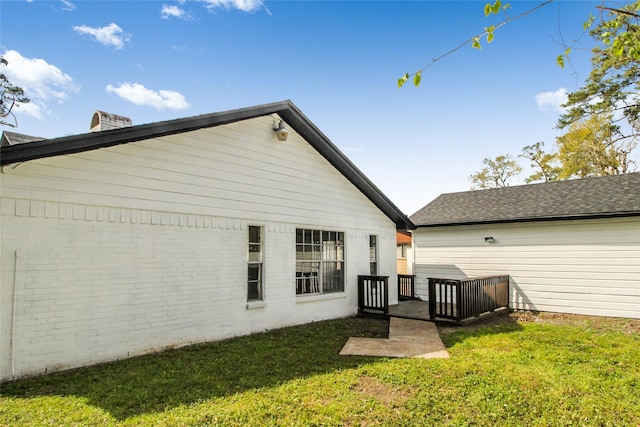 rear view of house featuring a lawn and a deck