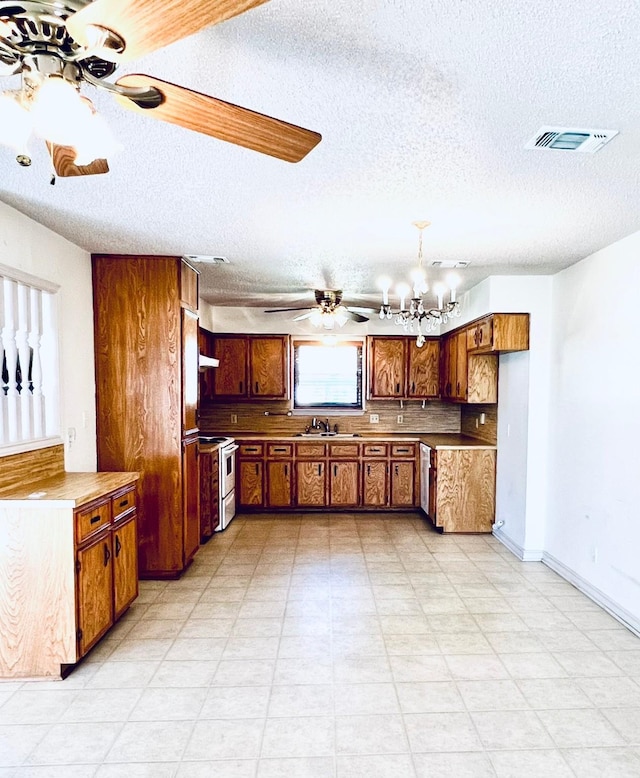 kitchen featuring white electric range oven, ceiling fan with notable chandelier, brown cabinets, and a sink