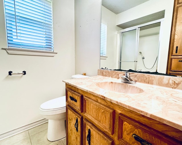 bathroom featuring tile patterned floors, vanity, a shower stall, and toilet