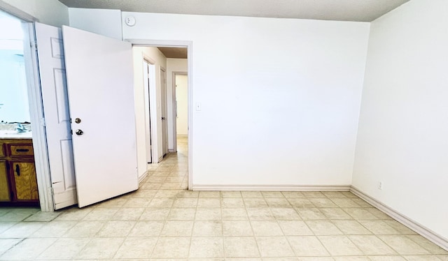 spare room with baseboards and a sink