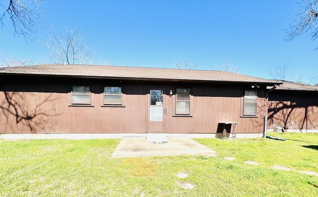 rear view of property featuring a yard, a patio, and roof with shingles