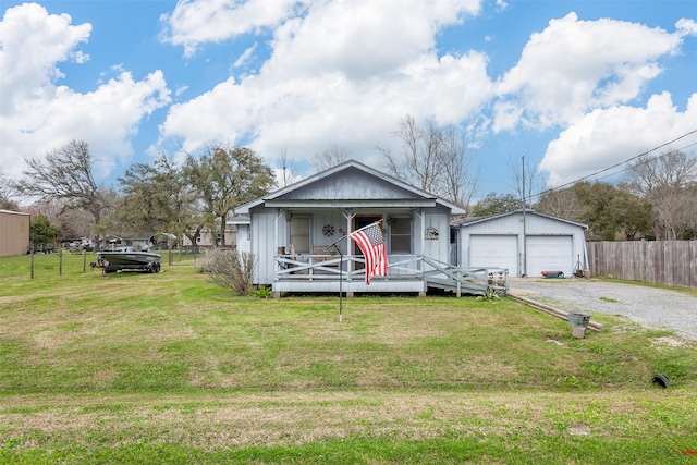 bungalow-style home with an outbuilding, fence, covered porch, a front lawn, and a detached garage