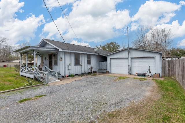 view of front of home with board and batten siding, fence, covered porch, and driveway