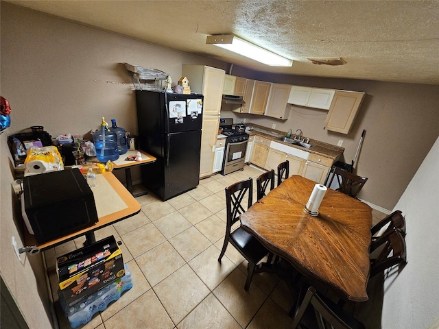 kitchen featuring under cabinet range hood, a sink, freestanding refrigerator, light tile patterned floors, and gas range