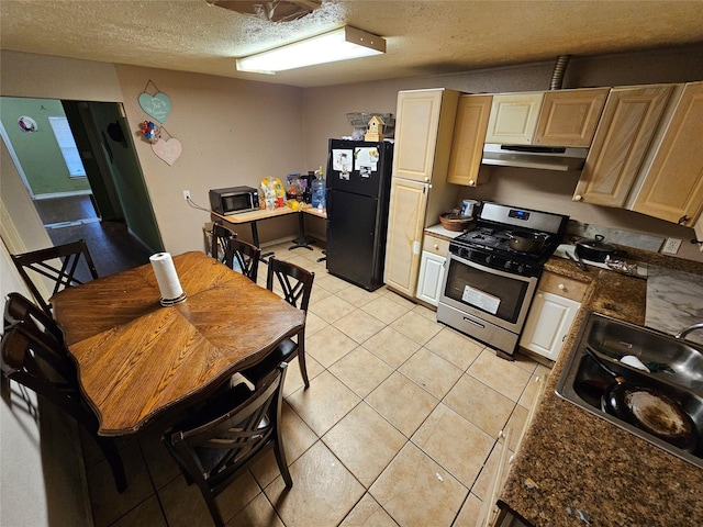 kitchen featuring black appliances, under cabinet range hood, light tile patterned flooring, a textured ceiling, and a sink