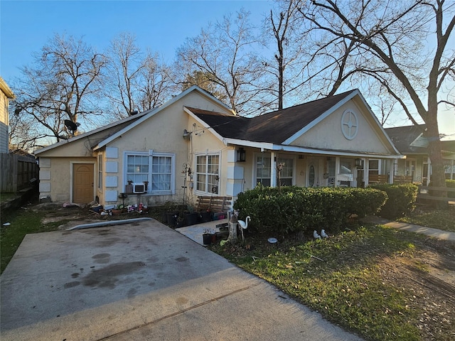 view of front facade featuring stucco siding, cooling unit, and fence