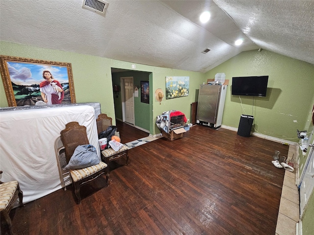 bedroom featuring visible vents, lofted ceiling, a textured ceiling, and wood finished floors