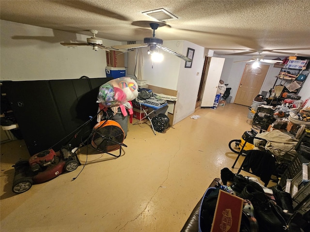 basement featuring a ceiling fan, visible vents, and a textured ceiling