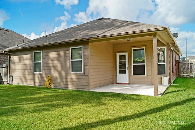 rear view of house featuring a patio, a yard, and fence