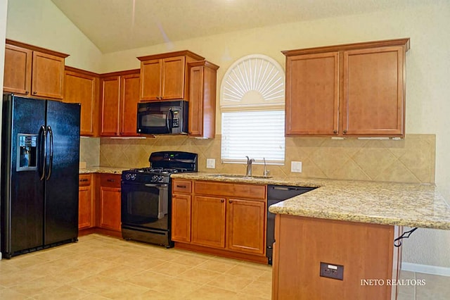 kitchen with black appliances, light stone counters, a peninsula, and a sink