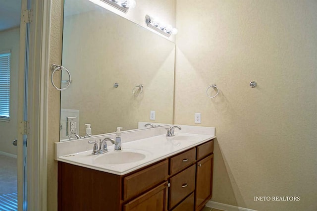 full bathroom with a sink, baseboards, and double vanity