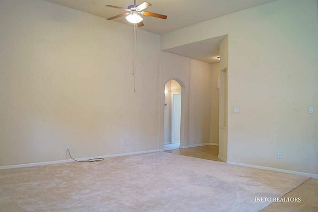 unfurnished room featuring baseboards, arched walkways, and ceiling fan