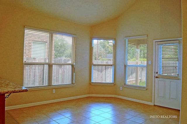 interior space with tile patterned floors, baseboards, and vaulted ceiling