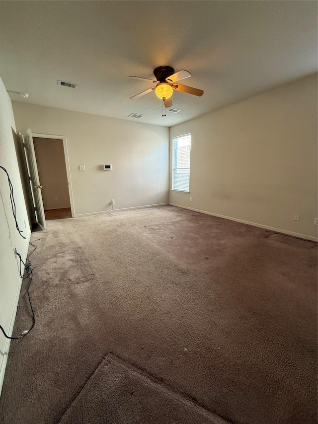 carpeted spare room featuring a ceiling fan, visible vents, and baseboards