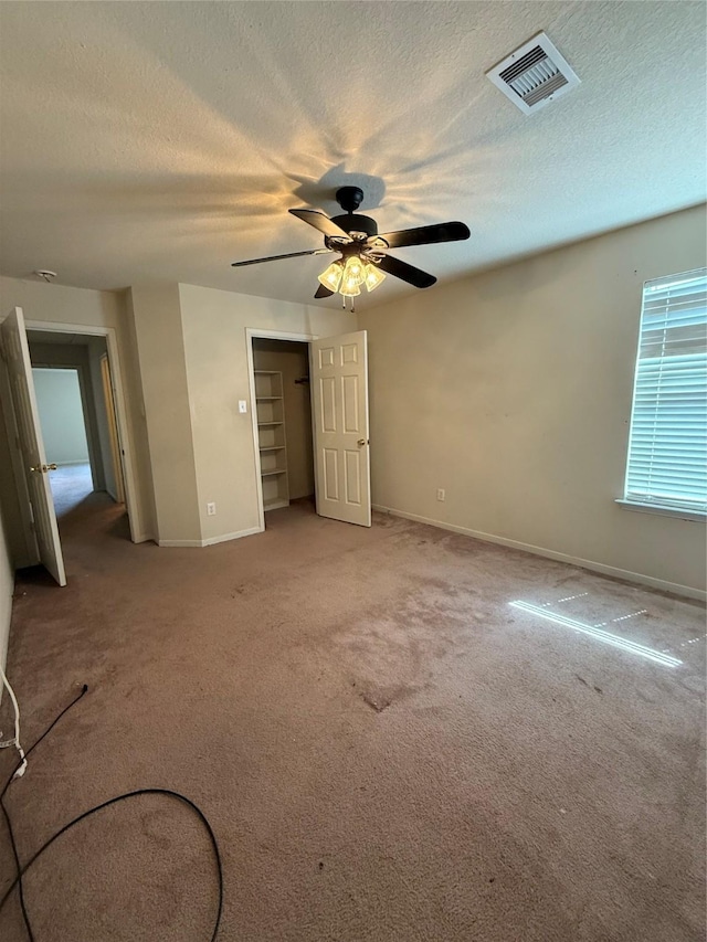 unfurnished bedroom with a textured ceiling, light colored carpet, visible vents, and baseboards