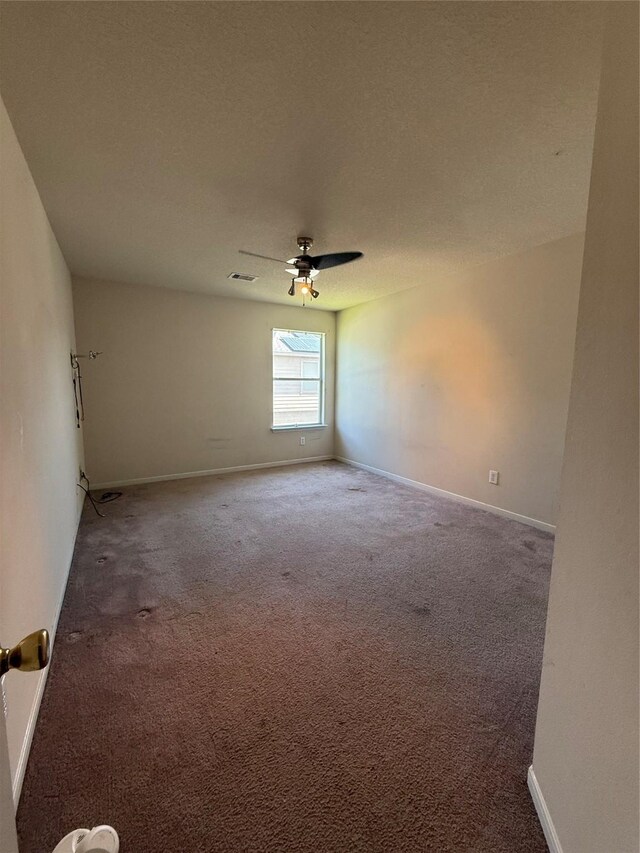 carpeted spare room with visible vents, baseboards, a textured ceiling, and a ceiling fan