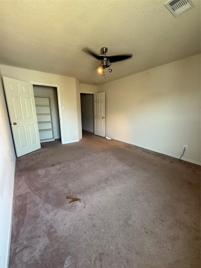 unfurnished bedroom with visible vents, carpet, a ceiling fan, and a textured ceiling