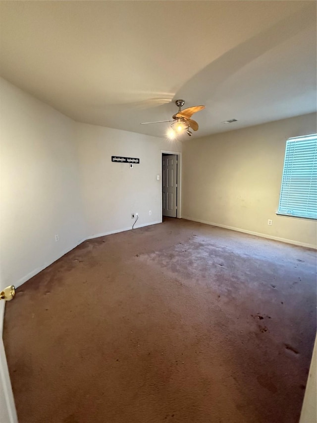 empty room featuring baseboards, a ceiling fan, and carpet