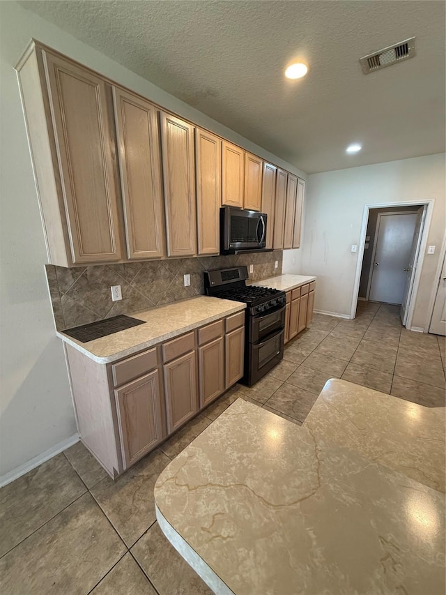 kitchen with decorative backsplash, range with two ovens, light tile patterned floors, and visible vents