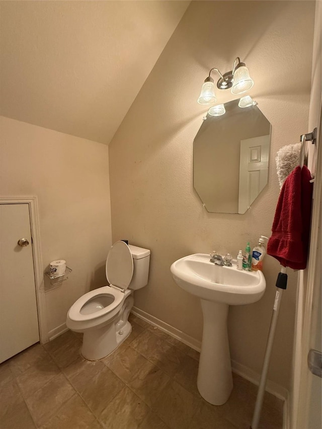 half bathroom with baseboards, toilet, and vaulted ceiling