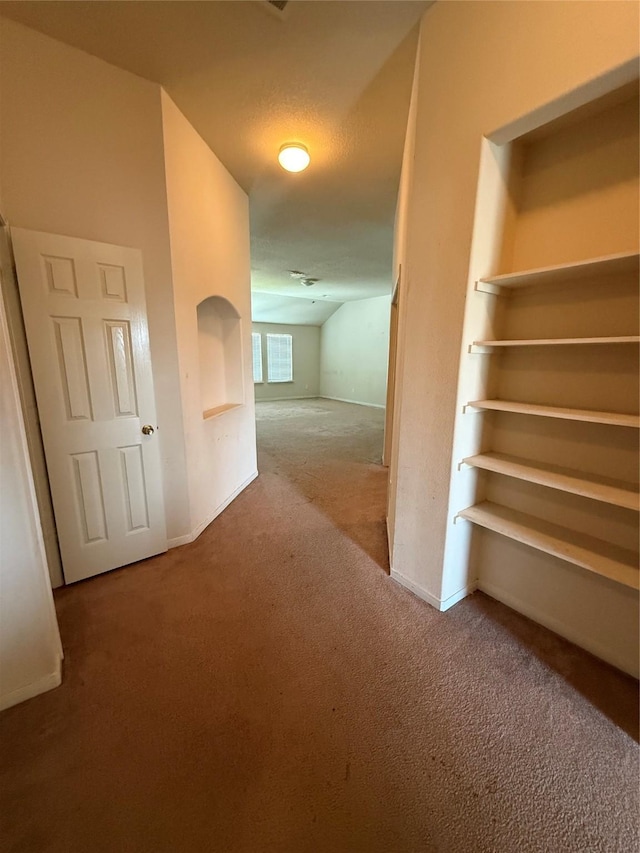 hall featuring vaulted ceiling, carpet flooring, and baseboards