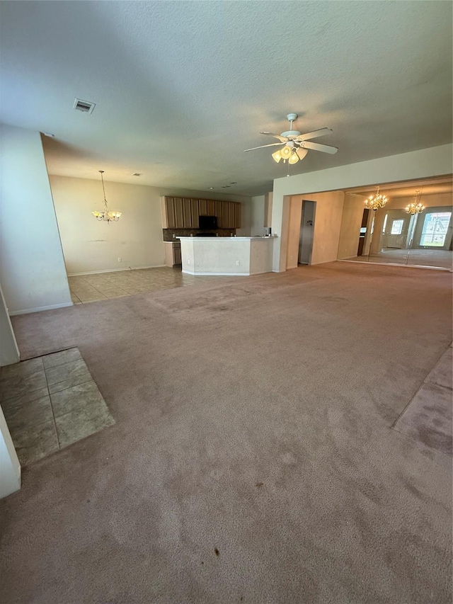 unfurnished living room with ceiling fan with notable chandelier, carpet, visible vents, and a textured ceiling