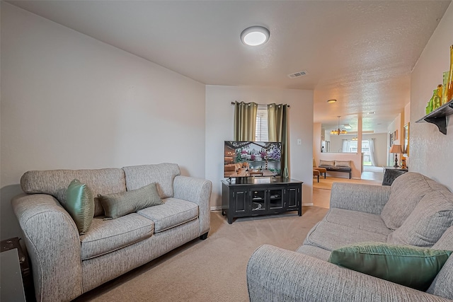 living area featuring visible vents, light colored carpet, and a textured ceiling