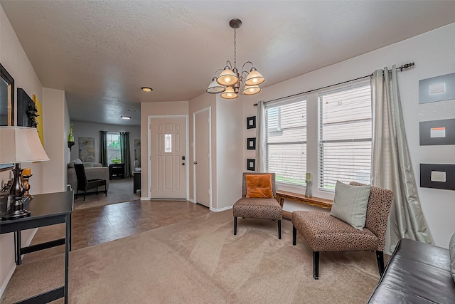 living area with light carpet, a notable chandelier, a healthy amount of sunlight, and a textured ceiling