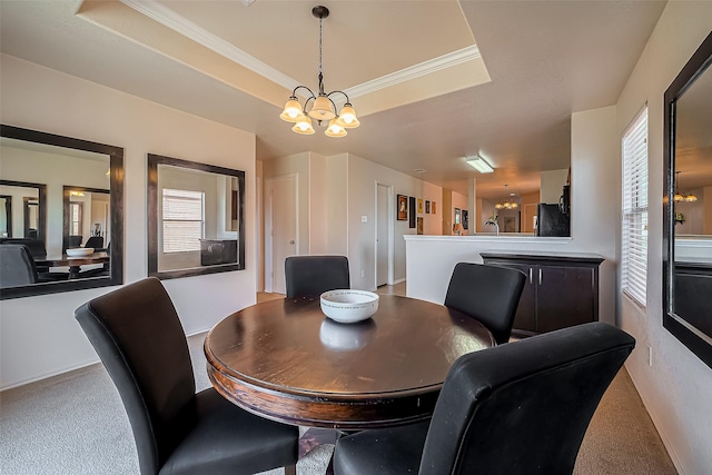 dining space with a notable chandelier, carpet floors, a tray ceiling, and ornamental molding