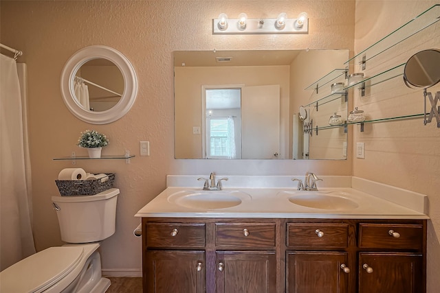 bathroom featuring double vanity, visible vents, toilet, and a sink