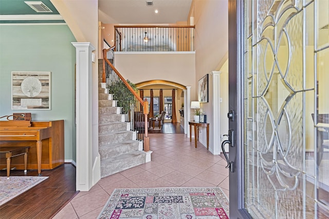 entrance foyer featuring stairway, visible vents, baseboards, arched walkways, and tile patterned flooring