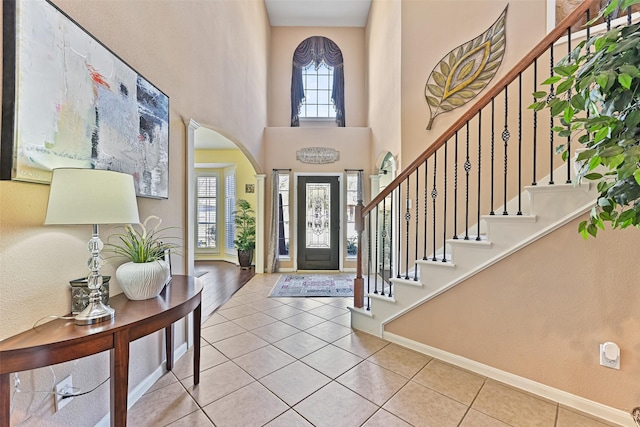 foyer entrance featuring arched walkways, tile patterned flooring, and stairs