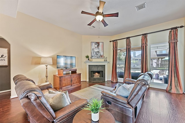 living area featuring visible vents, a tile fireplace, a ceiling fan, and dark wood-style flooring